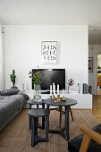 Set of three tables, grey sofa and TV on low, white sideboard in living room