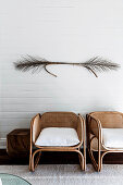 Designer rattan chairs with dried branches on white wall