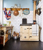 Alter Holzofen und Vintage Tisch in Küche mit weißer Fliesenwand