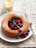 A wreath cake with berries and powdered sugar