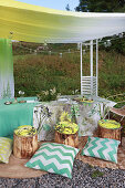 Set table, tree-stump stools and cushions under awning