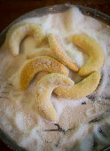 Baked vanilla crescent biscuits being rolled in sugar