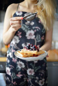 Woman is holding a plate with waffles and fruit
