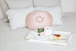 Kaffee, Kuchen und eine Rose auf einem Tablett auf dem Bett
