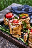 Stuffed aubergine rolls served on a table outdoors