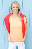 A young blonde woman wearing a yellow t-shirt with a red jumper over her shoulders