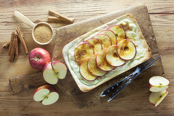 Tarte flambée with apples, sugar and cinnamon on a wooden surface