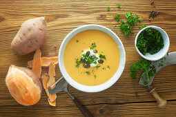 Sweet potato soup with ingredients on a wooden surface