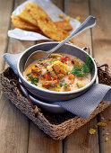 Seafood soup in a soup terrine with a spoon on a cork tray