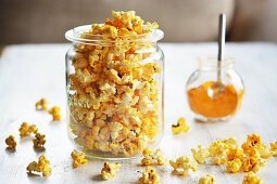 Popcorn with curry and salt in a jar next to a small jar of curry powder