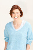 A red-haired woman wearing a blue jumper over a white top