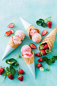 Gefrorenes Erdbeer-Sahne-Mousse serviert als Eiskugeln in Eistüten