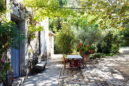 Table and vintage chairs on terrace outside Provençal house