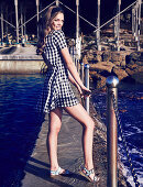 A young woman at a harbour wearing a black-and-white checked dress