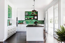 Kitchen island in white kitchen with green wall tiles