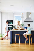 Woman with sons in open kitchen with cows island