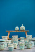 Türkis glasierte Übertöpfe und Vasen auf und vor einer Holzbank