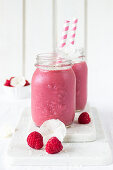 Jars of raspberry and coconut smoothie with straws