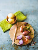 Red shallots on a chopping board and brown onions in a small copper bowl