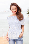 A brunette woman wearing a blue-and-white striped Carmen blouse