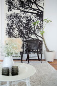 Round white side table in front of two chairs against large poster in living room