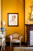 Baroque armchair below portrait on yellow wall
