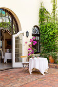 Table with white tablecloth in Mediterranean courtyard with terracotta floor tiles