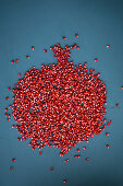 Pomegranate seeds arranged in the shape of a pomegranate on a blue background