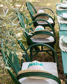 Bestickte Strohhüte auf den grünen Gartenstühlen am Tisch