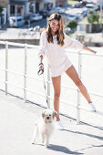 A girl wearing a white knitted jumper and shorts with a little dog