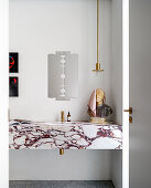 Marble vanity with bust, above pendant lamp and razor-shaped mirror in the bathroom