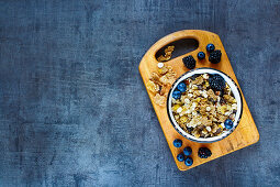 Top view of deliciousl breakfast table with granola in vintage bowl and fresh dark berries on grunge background