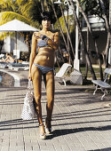 A young, short-haired woman wearing a bikini and holding a handbag