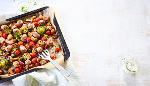 Sausages, mushrooms, tomatoes, broccoli and onions on a baking tray