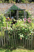 Paling fence surrounding cottage garden with greenhouse
