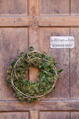 Wreath of ivy leaves and ivy flowers on old wooden door