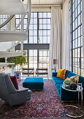 Blaue und graue Polstermöbel in offenem Wohnraum mit Glasfront und doppelter Raumhöhe