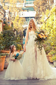 A bride wearing an elegant white wedding dress with a flower girl