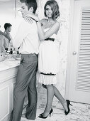 Junge Frau im Kleid mit Spaghettiträger und Mann im Hemd und Anzughose im Badezimmer (s-w-Aufnahme)