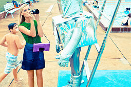 A blonde woman taking a photo of a child dressed as a robot at an open air pool