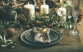 Weihnachtlich gedeckter Tisch mit Kerzen, Zweigen und Dekokugeln