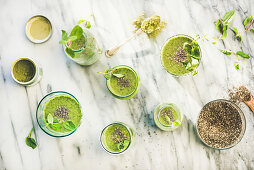 Veganer grüner Matcha-Smoothie mit Chia und Minze in Flaschen und Gläsern (Aufsicht)