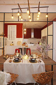 Festlich gedeckter Tisch vor halboffener Küche mit roter Wand