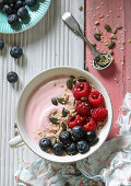 A smoothie bowl with raspberry yoghurt, fresh berries and seeds