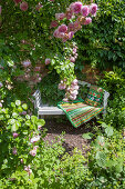 Romantischer Sitzplatz mit Gartenbank und Rosen