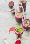 Fresh morning beetroot smoothie or juice in glasses with mint leaves, grey marble background, copy space