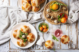 Hot Cross Buns auf gedecktem Ostertisch mit gefärbten Eiern und Getränk (Aufsicht)