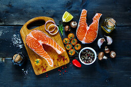 Two steaks of salmon with fresh ingredients for tasty cooking on rustic wooden background, top view, banner