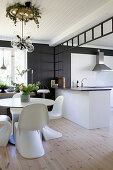 Dining table and designer chairs in front of white open-plan kitchen