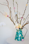 Origami birds made from painted paper hung from twigs